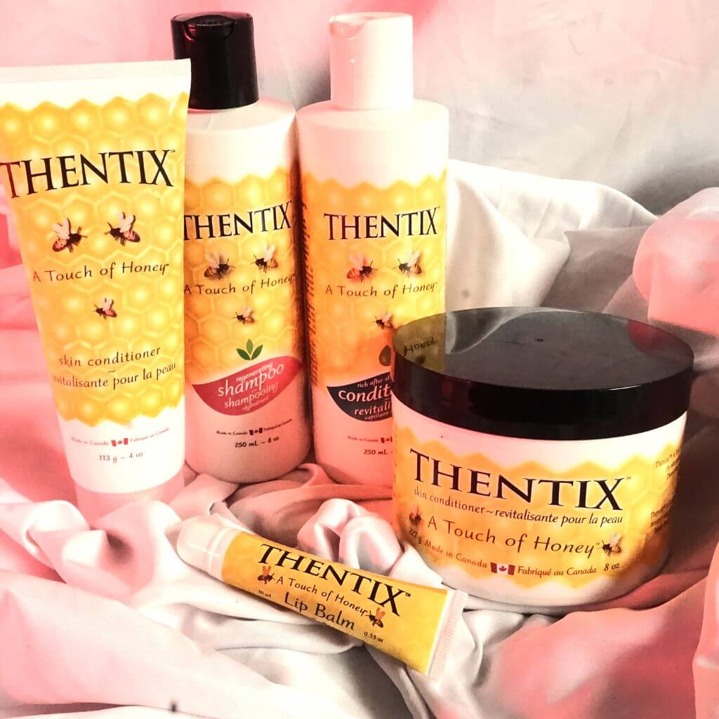 Thentix skin conditioner, hair care, and lip balm on a white and pink fabric background.